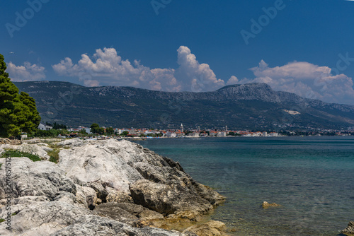 Bild auf Leinwand Panorama overlooking the city and monuments of Kastel in Croatia, pebbly beach D