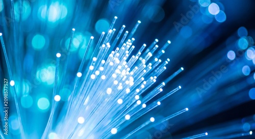 Abstract macro view of glowing blue fiber optic strands transmitting data signals in a dark environment representing high speed internet connectivity with blue light