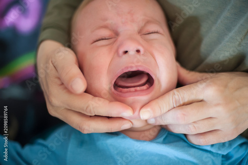 Little one's first tearful symphony as a tiny tooth begins its challenging emergence, bringing a wave of discomfort and a parent's gentle care