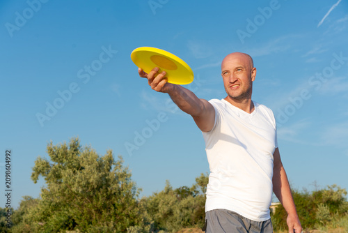 Obraz na płótnie Man is holding a yellow frisbee in his hand