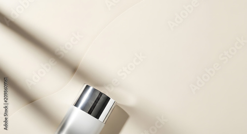 Silver cosmetic bottle cap with leaf shadows.