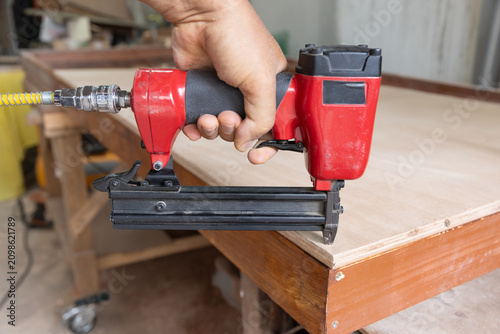 Nail gun is nailing on plywood in wood workshop.