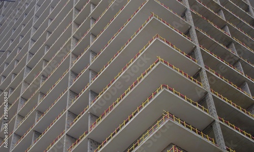 Modern concrete skyscraper under construction with yellow safety barriers and copy space