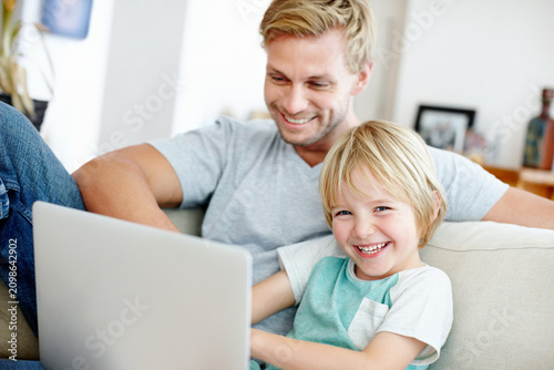 Laptop, relax and laughing with father and son on sofa for streaming service, bonding and movie subscription. Online film, love and multimedia search with man and portrait of child in family home