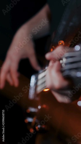 Extreme close up of bassist plucking strings on red electric bass guitar