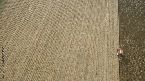 Fotografie Farmer riding tractor in a large green field during daytime