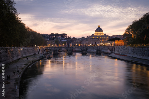 Beautiful twilight view of St. Peter's Basilica dome and Ponte Sant'Angelo bridge over the Tiber River at sunset in Rome, Italy