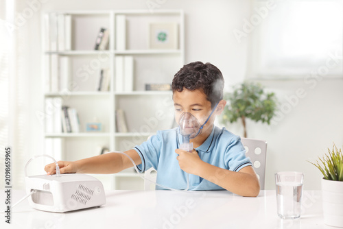 Little boy using a nebulizer machine with an inhalation mask