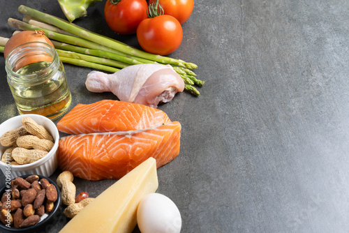 Foto Ketogenic diet ingredients with salmon, chicken, eggs and vegetables on dark bac