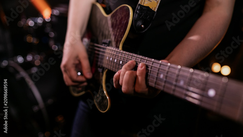 Rock guitarist playing energetic solo on electric guitar with warm concert bokeh