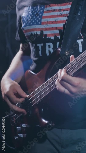 Bass guitarist performing on stage with patriotic shirt and dramatic blue lighting