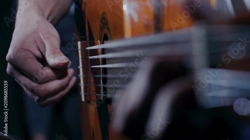 Detailed view of guitarist fingerpicking nylon strings on polished classical guitar