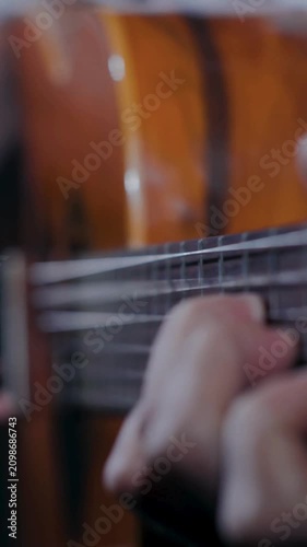 Close up hand forming chord on warm wooden acoustic guitar neck