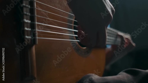 Intimate close up of fingers plucking classical guitar strings in low light