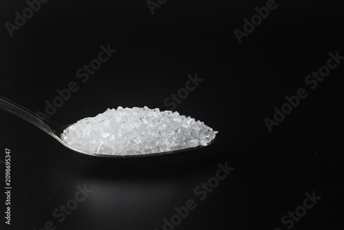 Canvastavla Spoonful of Epsom salt crystals over dark background with copy space