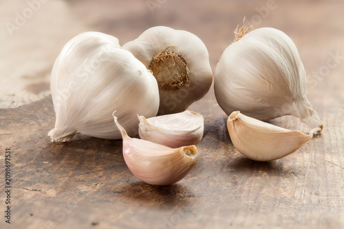 Foto Rustic composition of fresh whole garlic bulbs and scattered cloves on a wooden kitchen table, healthy cooking and culinary concept
