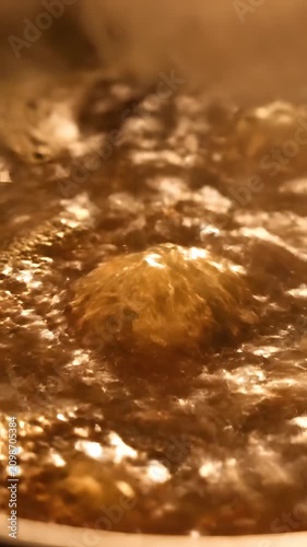 Macro view of hot boiling golden liquid with many bubbles.
