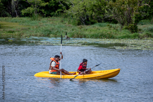 SIGIRIYA, SRI LANKA - JUNE 10, 2026 : A father and son paddle a kayak on Thalkote Lake at Sigiriya in Sri Lanka.