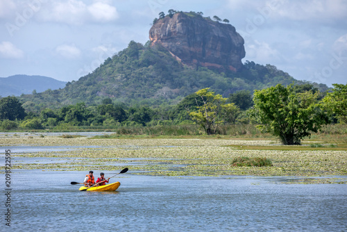 SIGIRIYA, SRI LANKA - JUNE 10, 2026 : A father and son paddle a kayak on Thalkote Lake at Sigiriya in Sri Lanka. In the background stands Sigiriya Rock.