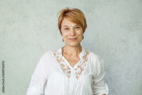 Indoor portrait of mature woman with a cute smile and natural look proudly showing her wrinkles representing authenticity healthy skin and a positive outlook on aging