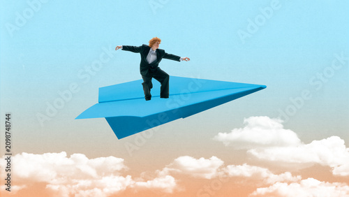 Foto Businessman balancing on giant paper airplane above clouds