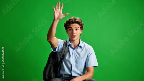 Enthusiastic student raising hand to ask a question on green screen