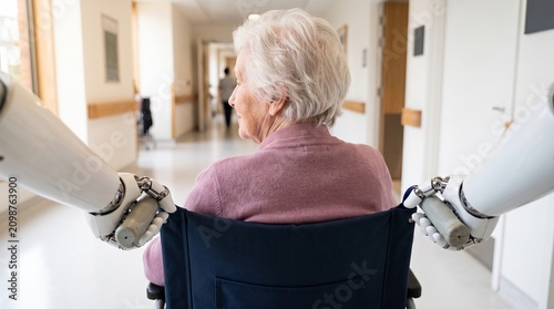 Humanoid Robot Assisting Senior Woman in Wheelchair at Healthcare Facility