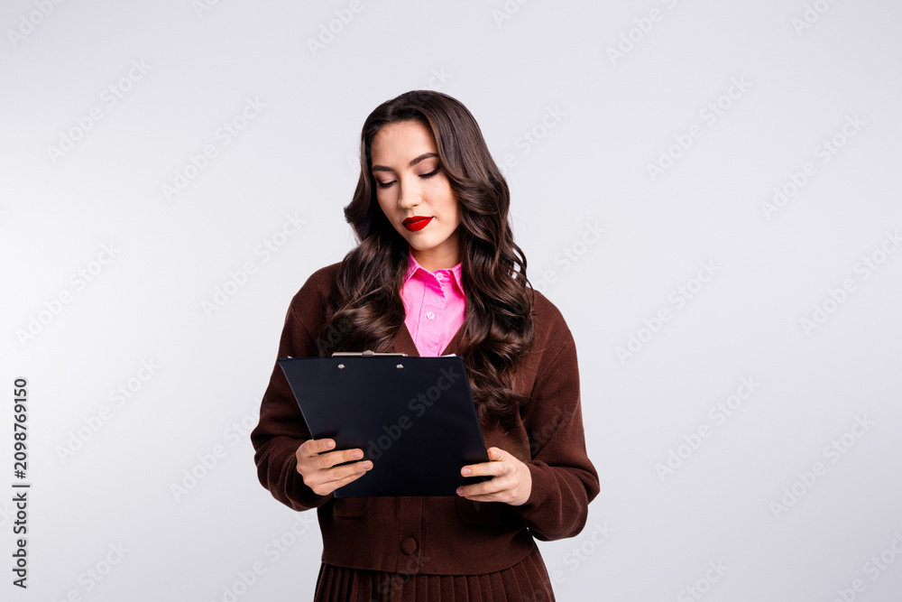 Obraz premium Young professional businesswoman holding clipboard in elegant attire on white studio background