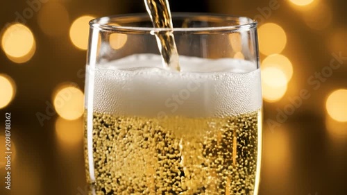 Sparkling golden drink being poured into a glass with festive bokeh