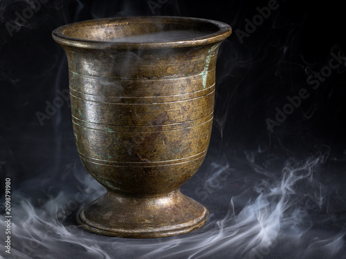 Antique bronze goblet with smoke on black background