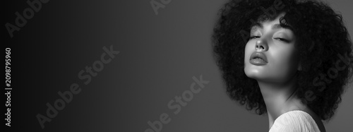 FINE ART SFUMATO PORTRAIT OF A BEAUTIFUL YOUNG BLACK WOMAN WITH NATURAL CURLY HAIR AND EYES CLOSED IN PEACEFUL EMOTION ON LIGHT GREY BACKGROUND WITH NEGATIVE SPACE