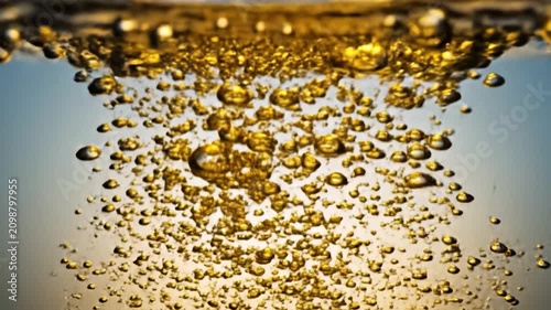 Dynamic golden bubbles rise in clear sparkling water