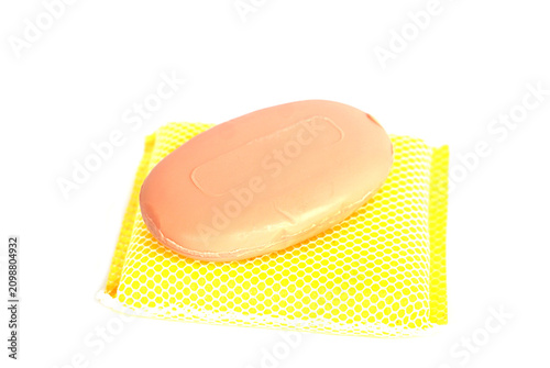 Natural bar soap placed on a yellow mesh soap saver against a clean white background. Personal hygiene and skincare concept featuring a simple bathroom essential with a minimalist design.