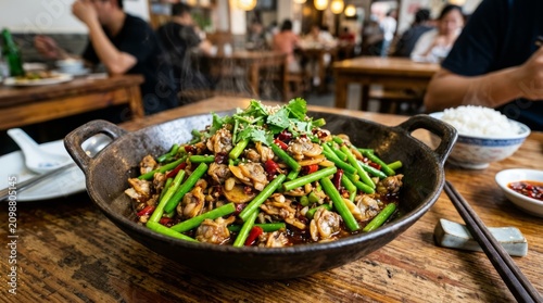 Stir-fried beef with fresh green vegetables in traditional wok on wooden table.