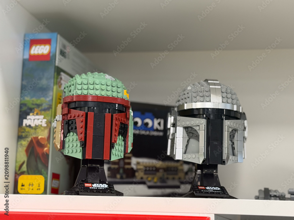 Fototapeta premium Two lego star wars helmet builds displayed on a shelf with toy boxes in the background