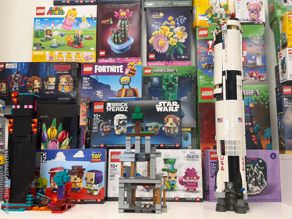 Fototapeta premium Colorful display of lego sets and built models with a tall rocket, game and movie themed boxes, arranged on shelves in a toy store