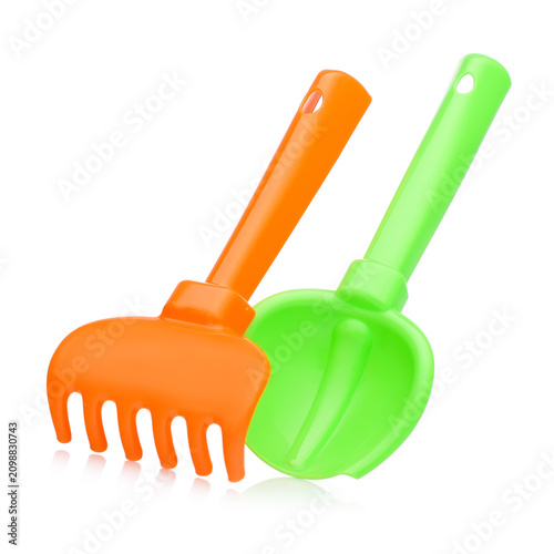 Orange plastic toy rake and green shovel set on white background