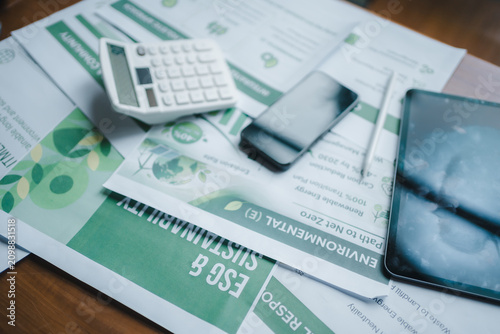 ESG report sustainability corporate strategy green finance auditing digital workspace, calculator smartphone tablet stylus on environmental document planning net zero carbon footprint reduction goals