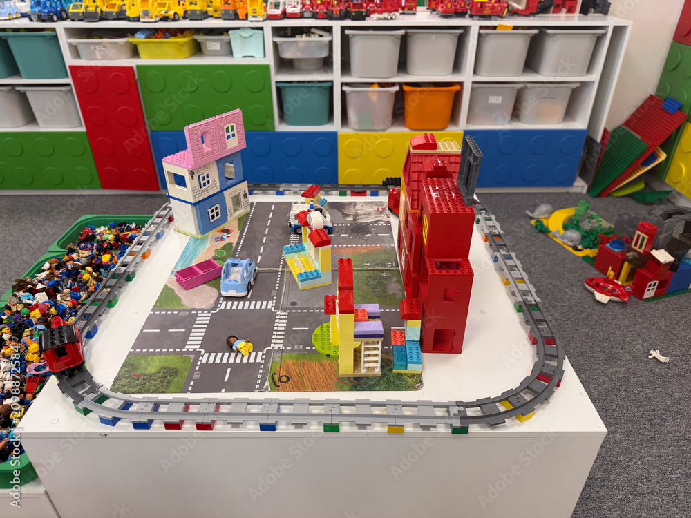 Obraz premium Colorful lego city play table in a classroom with houses, roads, cars and storage shelves in the background