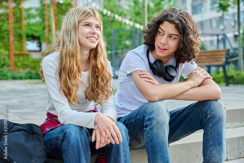 Smiling teenage girl talking to boyfriend outdoors