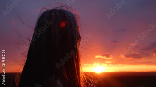 Peaceful woman watching the vibrant sunset, feeling the gentle breeze