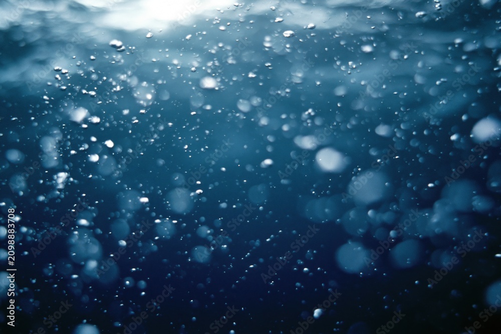 Naklejka premium The Underwater Bubbles in Deep Blue Ocean Creating Dreamy Light Particles
