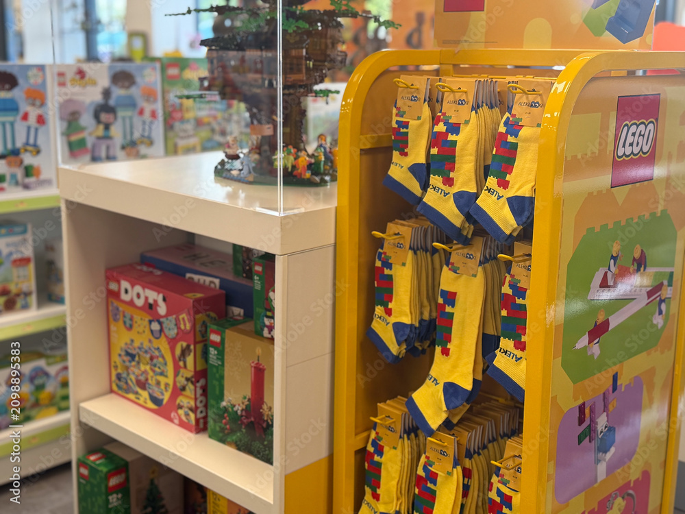 Obraz premium Colorful toy store display with lego socks hanging on a rack and shelves of boxed toys in the background
