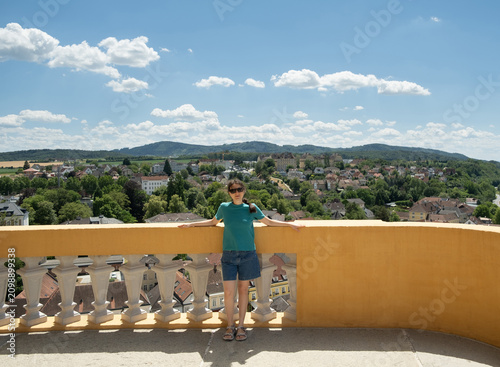Happy woman tourist looking at camera on the scenic observation terrace of Melk Abbey, Austria