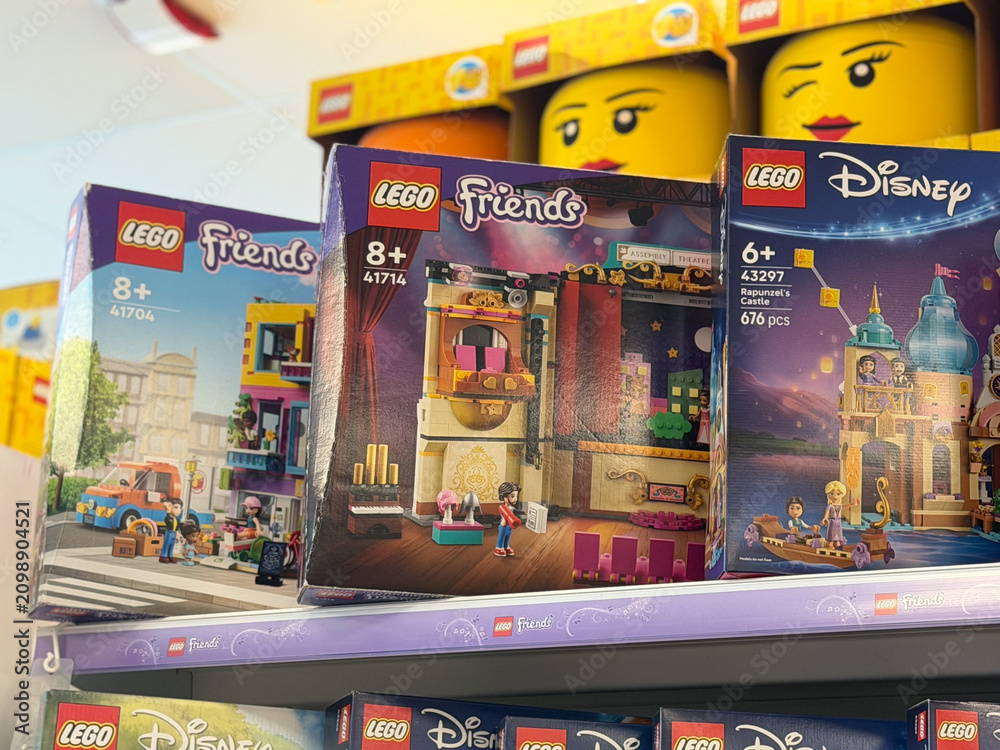 Fototapeta premium Colorful lego toy boxes displayed on a retail store shelf in a toy aisle, showing friends and disney playsets for kids and gift shopping.