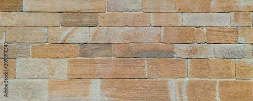 Modern sandstone brick wall background with multicolored blocks and textured surface for architecture