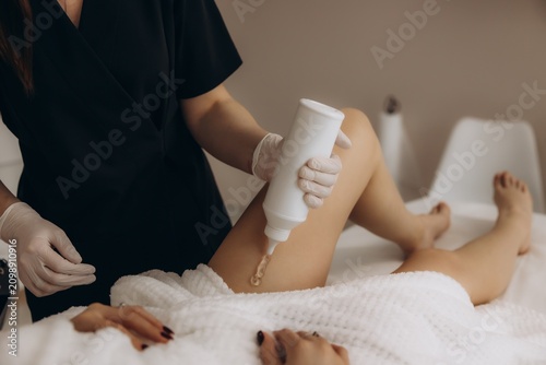 Cosmetologist applying gel before laser hair removal treatment