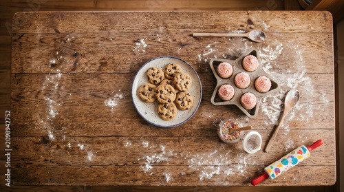 Rustic Baking Scene: Chocolate Chip Cookies and Pink Cupcakes on a Wooden Table
