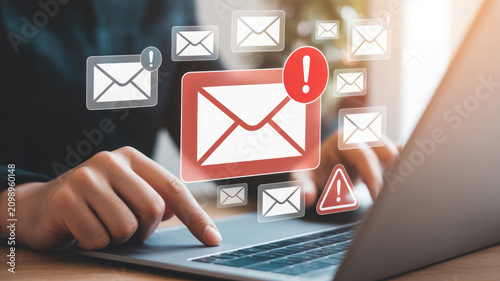 Digital email notification concept with urgent alert symbols floating above a laptop computer keyboard