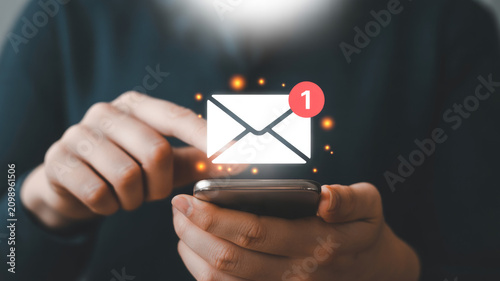 Close up of a person interacting with a digital email notification icon floating above their smartphone